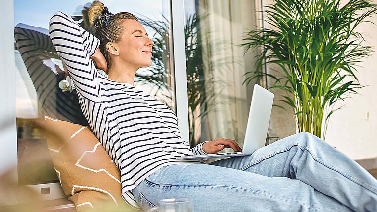 Frau entspannt sich mit Laptop auf der Terrasse