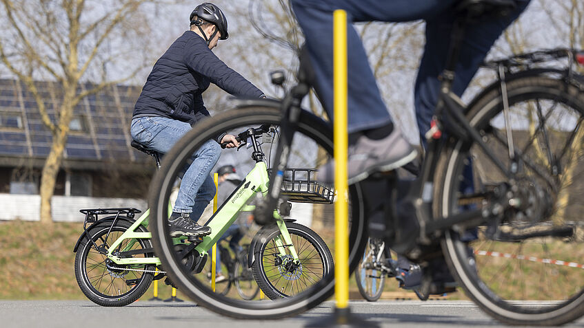 Das Bild zeigt einen Teilnehmer beim Fahrsicherheitstraining der BGHW, der auf dem Pedelec durch einen Slalomparcours fährt.