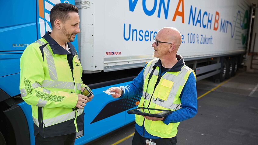 Michael Schneider im Gespräch mit einem Fahrer vor E-LKW der Zufall Logistics Group.