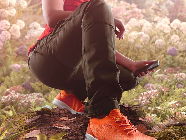 Junge Frau in der Natur mit roten Sicherheitsschuhen im Sneaker-Look