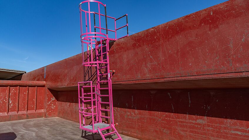 Im Ladebereich eines Transportschiffs befindet sich eine mobile Einstiegskonstruktion an einer der beiden länglichen Seiten des Schiffs.