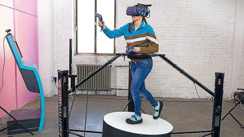 Frau auf einem omnidirektionalen Laufband mit VR-Brille.