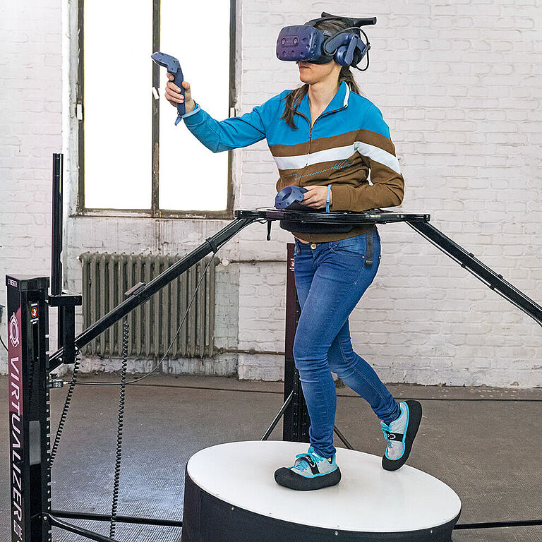 Frau auf einem omnidirektionalen Laufband mit VR-Brille.