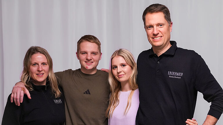 Familie Eberhard steht Arm in Arm. Alle schauen freundlich in die Kamera. 