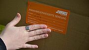 Orangefarbener Aufkleber mit der Aufschrift „Annahmeverweigerte Sendung“ auf Paket bei Zufall.