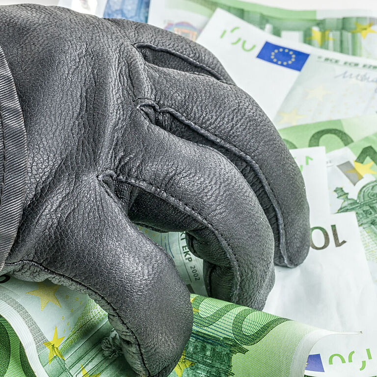 Hand mit schwarzem Lederhandschuh entwendet Euro-Geldscheine