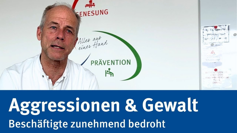 Der Interviewpartner, Dr. Christoph Reimertz, schaut an der Kamera vorbei. Unten ist ein Schriftzug auf blauem Hintergrund der den Titel des Videos nennt: Aggressionen und Gewalt gegen Rettungskräfte und Beschäftigte