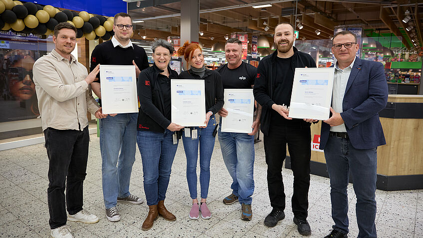 Gruppenbild von vier Ersthelfern, zwei Arbeitsschutzverantwortlichen von Kaufland und Aufsichtsperson Norbert Kaiser von der BGHW 