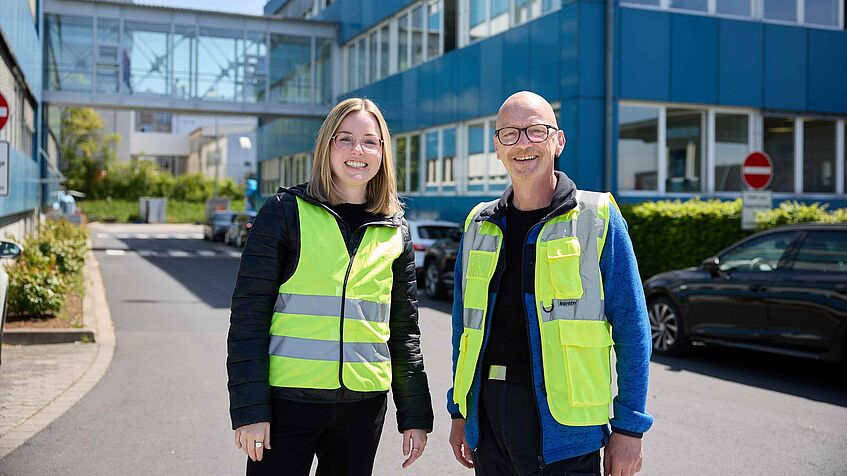 Tessa Erzgräber und Michael Schneider in Warnwesten vor dem Hauptgebäude der Zufall Logistics Group in Fulda.