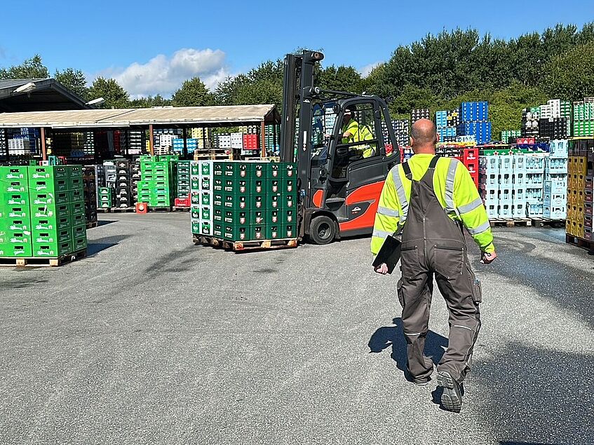 Dirk Boßmeyer geht über das Gelände des Getränkelogistikers Essmann. Vor ihm stapeln sich die Kästen mit leeren und vollen Flaschen. 