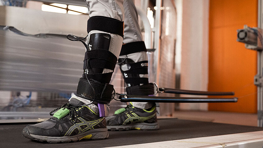 Blick auf die Unterschenkel und Füße einer Person, beides ist für einen Versuch verkabelt.