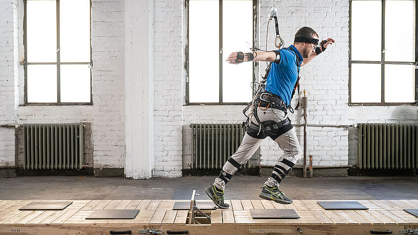 Ein Mann in einem Ganzkörpermessanzug geht einen Stolperparcour entlang.