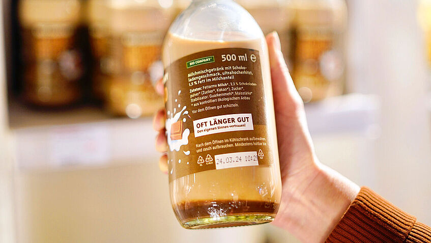 Glasflasche mit Kakao, auf dem Etikett steht ein Hinweis, dass das Produkt auch nach Ablauf des Mindesthaltbarkeitsdatums noch gut ist. 