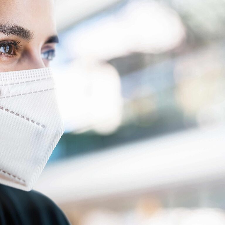 Eine junge, dunkelhaarige Frau trägt eine FFP2 Maske