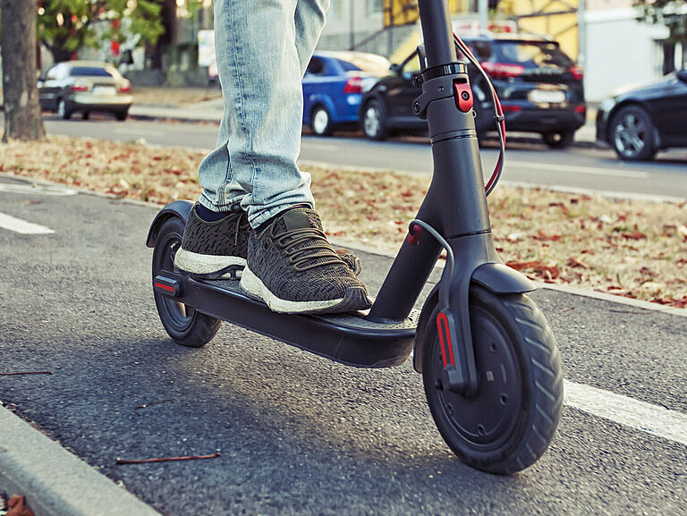 Ein E-Scooterfahrer fährt auf dem Radweg