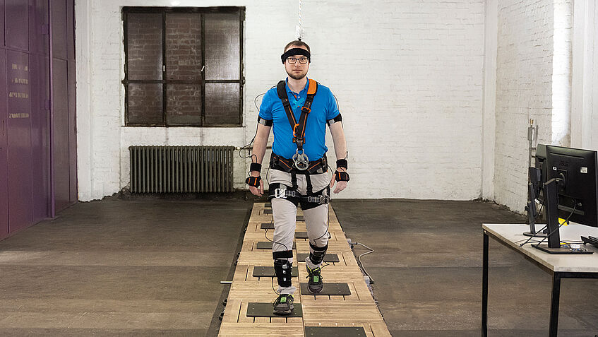 Ein Mann in einem Ganzkörpermessanzug geht einen Stolperparcour entlang.