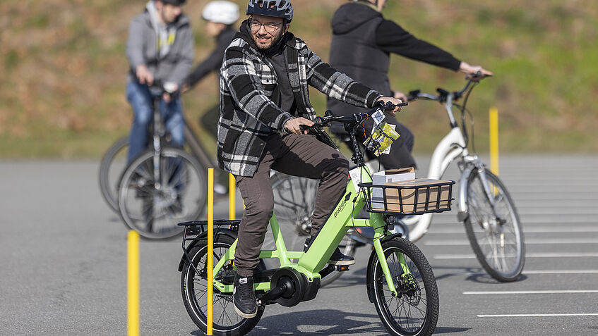 Bild zeigt einen Teilnehmer beim Fahrsicherheitstraining, der auf einem grünen Pedelec durch den Slalomkurs fährt.
