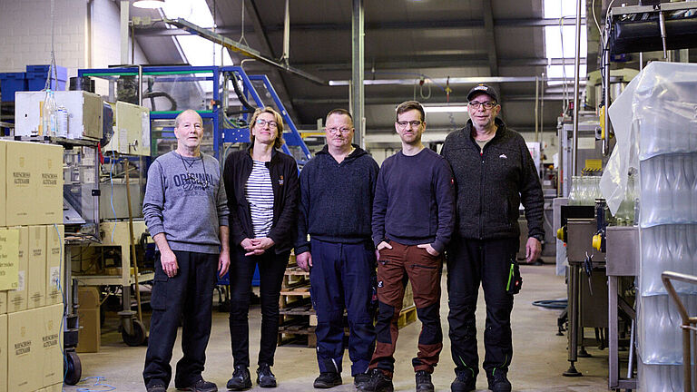 Beschäftigte der WG Mayschoss-Altenahr, (von links) Hans-Joachim Raths, Astrid Rickert, Günter Schumacher, Pascal Legrand und Manfred Sebastian, stellen sich in der Abfüllhalle zum Gruppenfoto. 