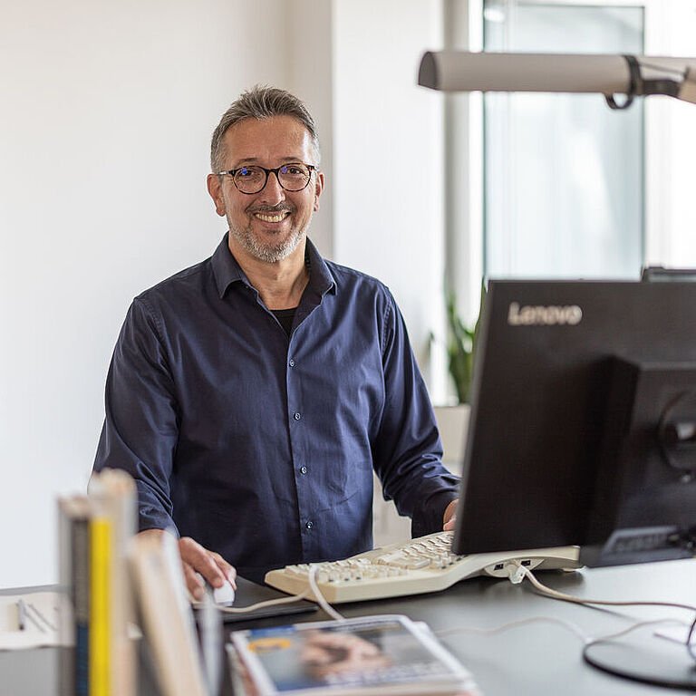 Karl-Josef Thielen am Schreibtisch vor PC, lächelt in Kamera 