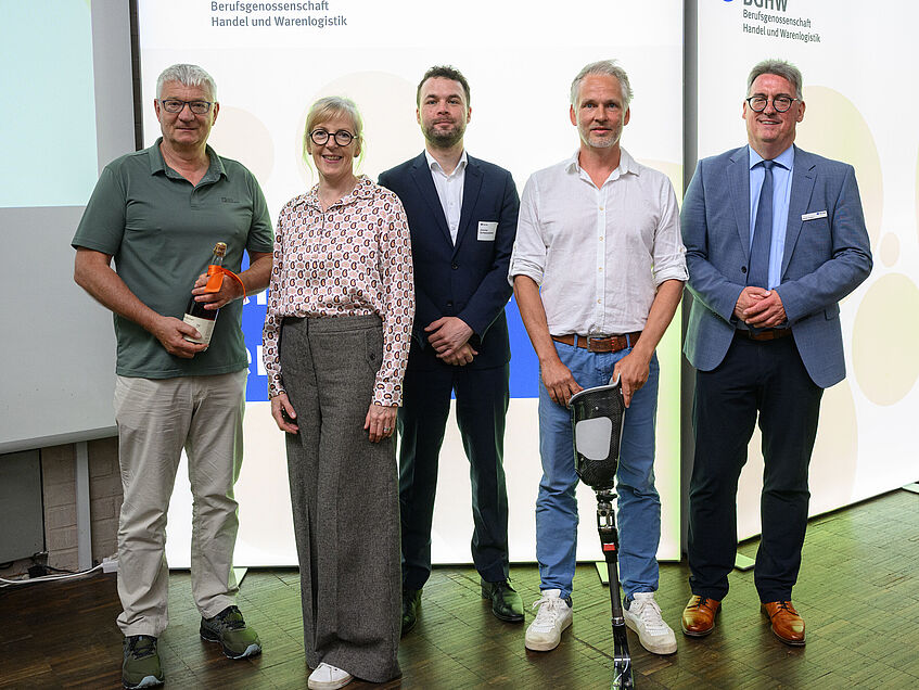 Sie stehen auf der Bühne und schauen freundlich in die Kamera. Die Dozentin und Dozenten, die beim BGHW-Reha-Forum über die Möglichkeiten und Entwicklungen zum Thema Sport und Teilhabe referierten. Von links: Peter Richarz, Sabine Drisch, Joscha Schwarzwälder, Dr. Sebastian Benner, Martin Kögler.