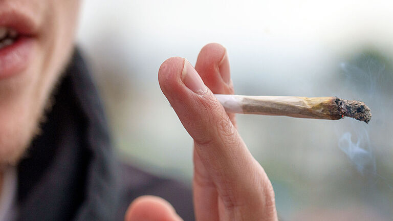 Das Bild zeigt eine Hand, die einen brennenden Joint hält. Das Bild wurde bei der Studie Cannabis und Autofahren aufgenommen.