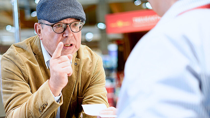 Das Bild zeigt einen wütenden Kunden an der Kasse, der mit dem Finger droht.