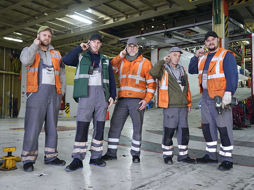 Fünf Hafenarbeiter mit Gehörschutz stehen nebeneinander im Frachtschiff.