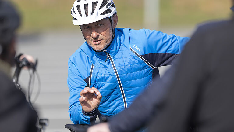 Das Bild zeigt Uwe Neubert aus dem BGHW-Trainerteam, der Teilnehmenden am Fahrsicherheitstraining erklärt, wie man sicher mit dem Pedelec unterwegs ist.