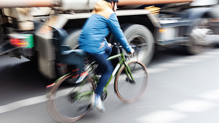 Das Bild zeigt einen Radfahrer, der neben einem Lkw fährt.