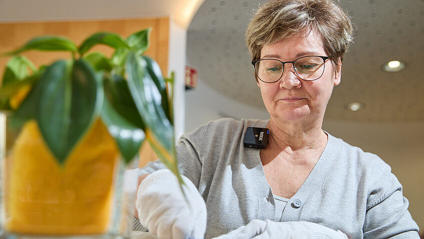 Eine Teilnehmerin hat ihre rechte Hand in einem weißen Leinensack, dem Fühlsäckchen, in dem sie erraten soll, welche Gegenstände sich darin befinden. 