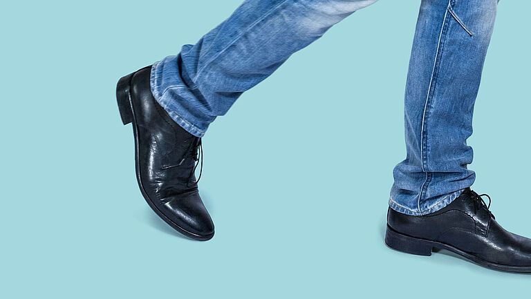 Zwei Beine in Jeans und zwei schwarze Schuhe. 