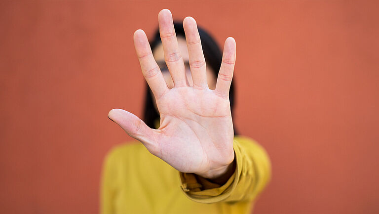 Frau macht mit Hand ein Stopzeichen.