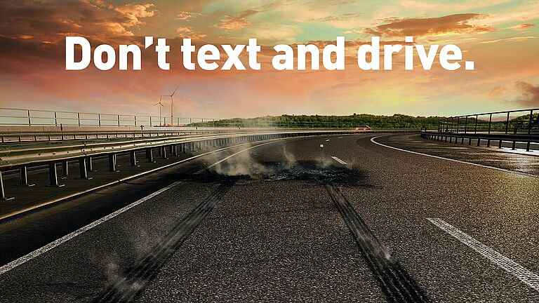 Eine Autobahn in der Dämmerung. Die Fahrbahn zeigt eine verkohlte Stelle eines Unfalls.