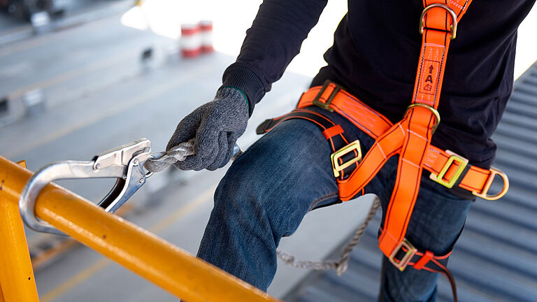 Mitarbeiter mit PSAgA sichert sich an einem Gerüst.