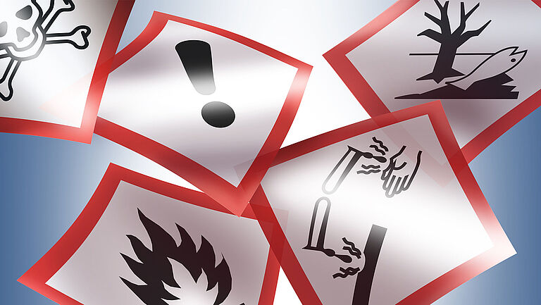 Fünf GHS Gefahrstoffsymbole sind auf blauem Hintergrund fliegend abgebildet