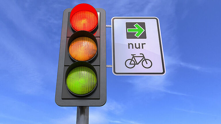 Das Bild zeigt eine rote Ampel und daneben steht der grüne Pfeil für Radfahrende
