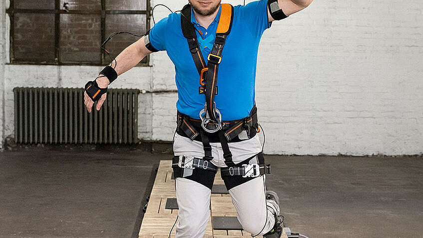 Ein Mann in einem Ganzkörpermessanzug geht einen Stolperparcour entlang und kommt auf den Betrachter zu.