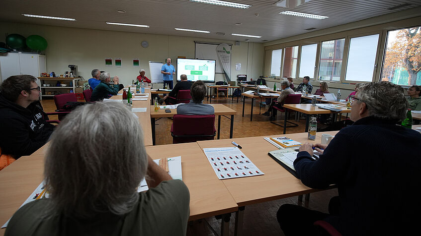 Die angehenden Sportcoaches sitzen im Seminarraum in Hufeisenform zusammen