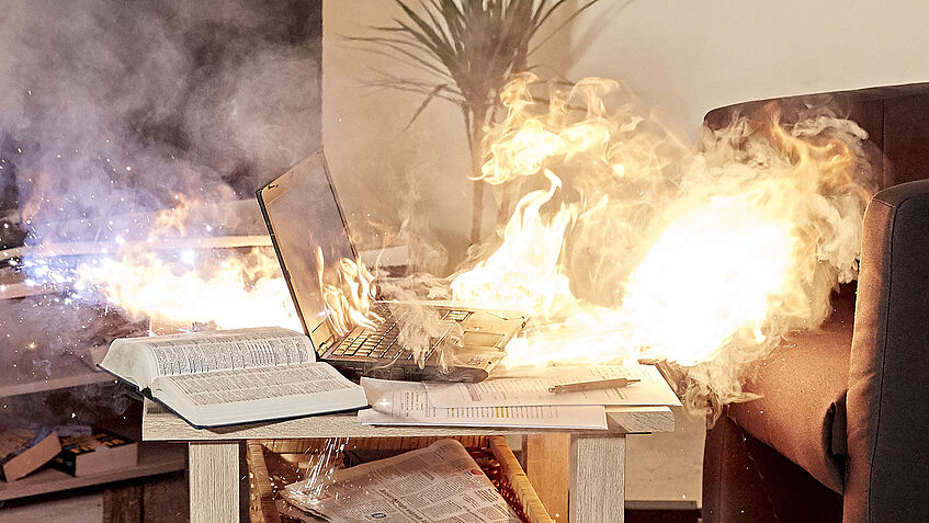 Auf einem Beistelltisch im Wohnzimmer steht ein Laptop, der in Brand geraten ist.