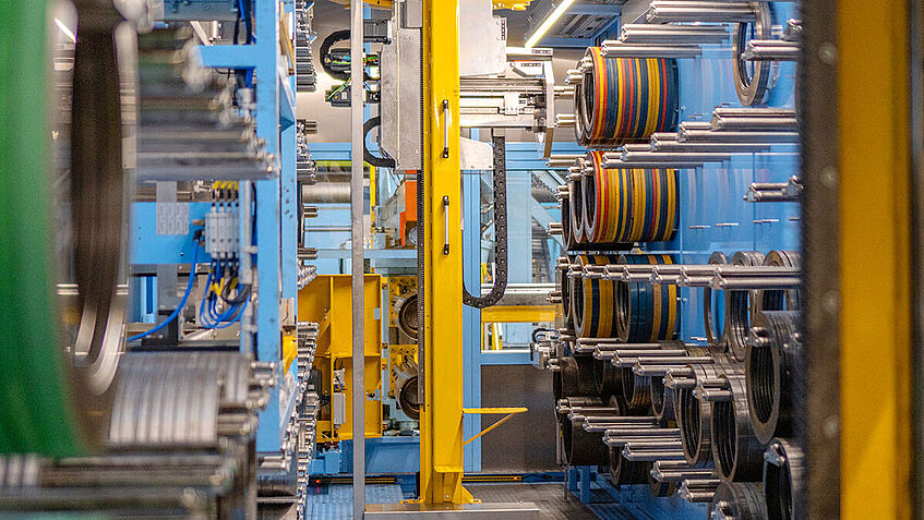 Blick in einen Raum mit zahlreichen Stahlringen, die an beiden Seiten der Wände hängen, in der Mitte steht ein Roboter.