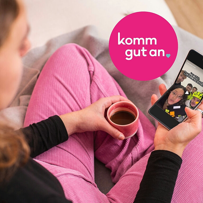 Eine junge Frau im Schneidersitze schaut sich ein TikTok-Video an
