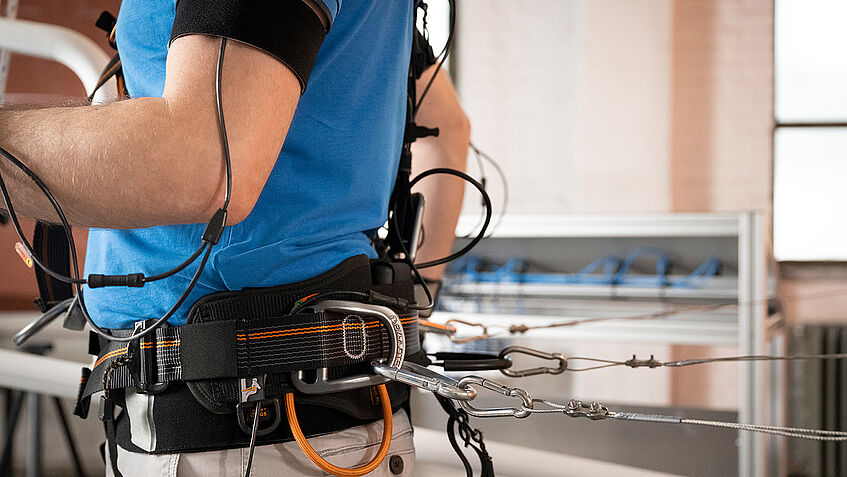 Blick auf den Rücken und die Hüfte einer Person, die mit mehreren Geräten verkabelt ist.