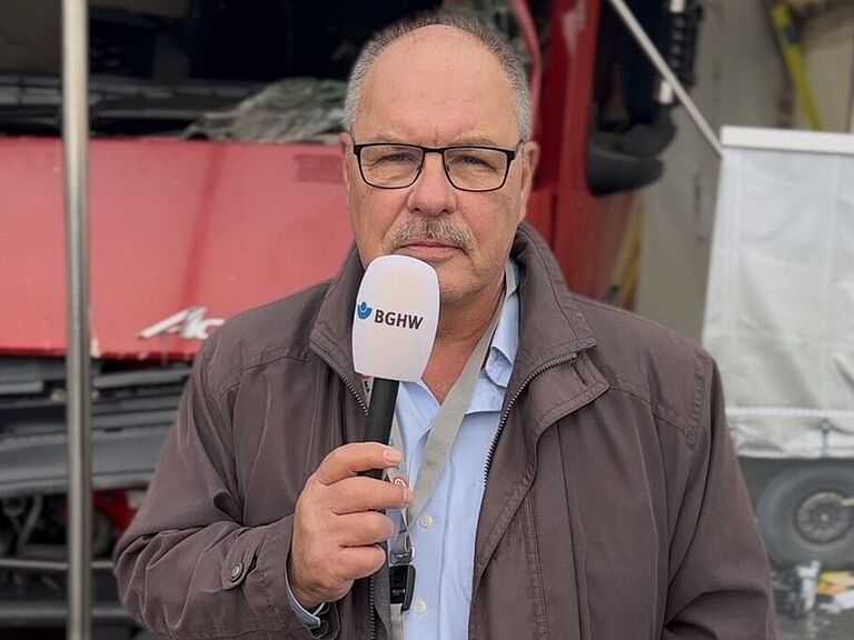 Dieter Schäfer mit Mikrofon in der Hand vor dem LKW-Exponat
