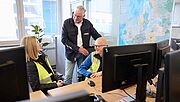 Tessa Erzgräber, Dr. Christoph Helmke und Michael Schneider im Gespräch im Büro vor Computermonitoren.