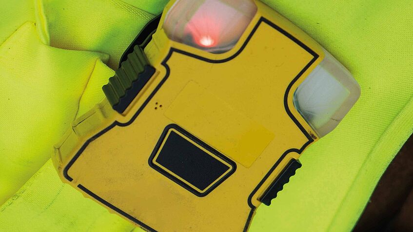 Mitarbeitende befestigen Transponder an Kleidung oder Helm