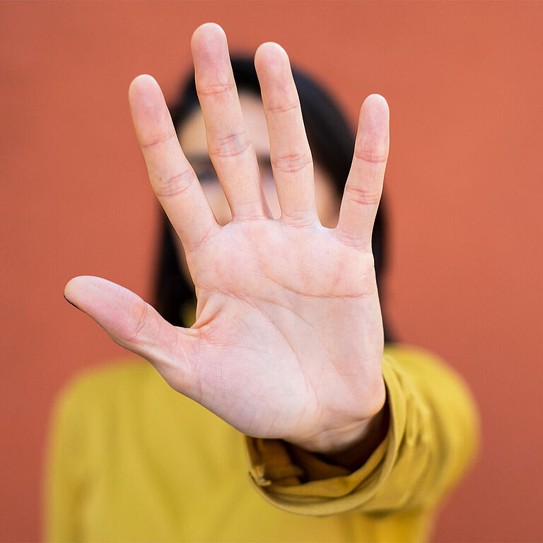 Frau macht mit Hand ein Stopzeichen.