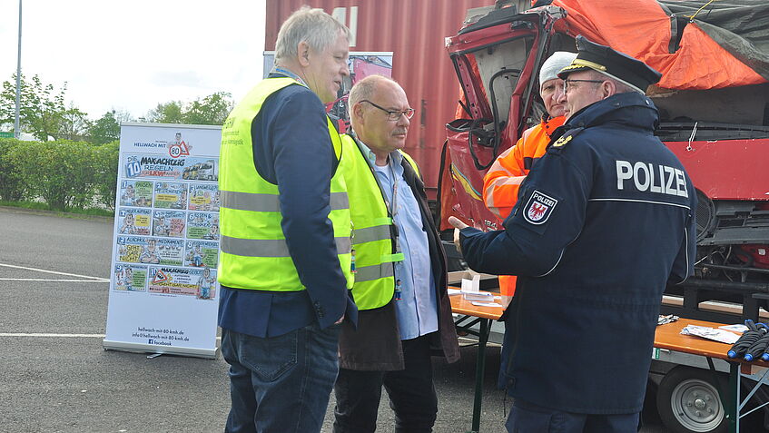 Vier Männer im Gespräch vor dem Unfall-Exponat LKW-Kabine