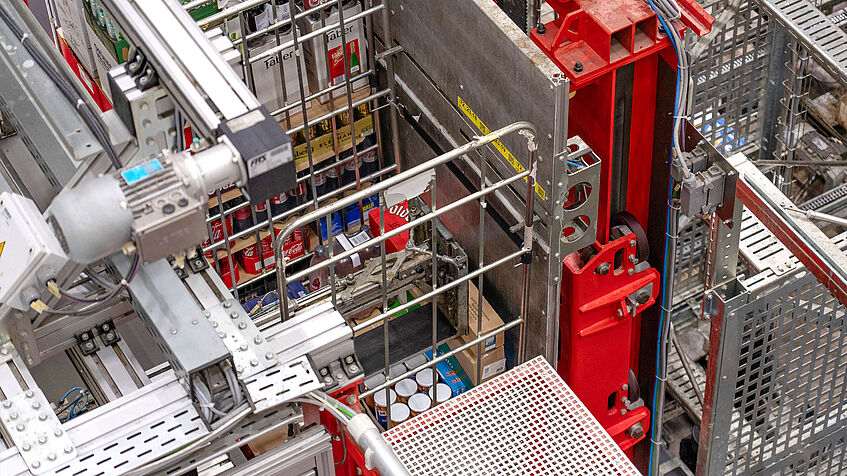 Blick in ein automatisiertes Logistikzentrum auf einen Rollcontainer mit Gummispanngurt