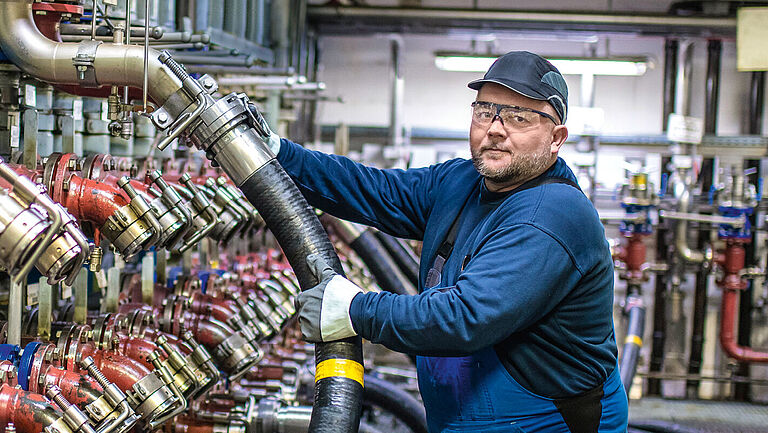 Mitarbeiter im Schlauchbahnhof von Fuchs Lubricants Germany beim Anschließen eines Schlauchs