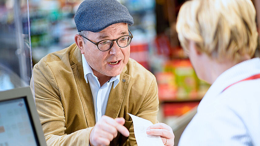 Das Bild zeigt einen wütenden Kunden an der Supermarktkasse